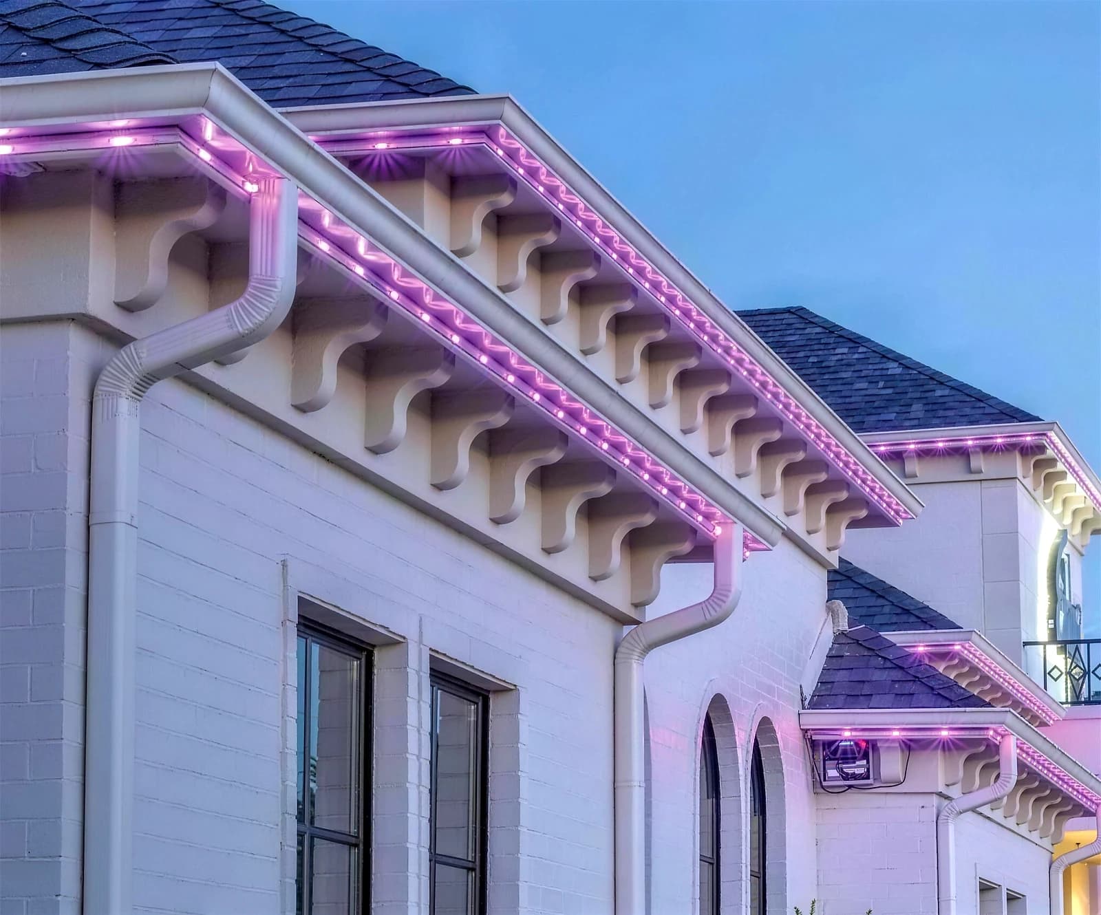 Modern home facade showing permanent LED lighting displaying festive red and green along the roof eaves